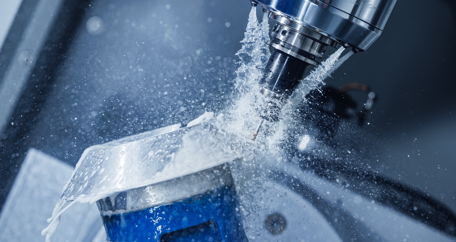 CNC milling of a precision metal component with coolant during machining.